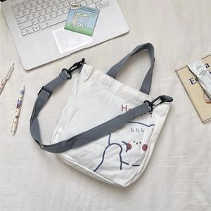 Detalle del bolso tote de lona con estampado de oso y correa gris ajustable