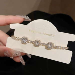 Detailaufnahme eines vergoldeten Armbands mit drei quadratischen Zirkonia-Steinen