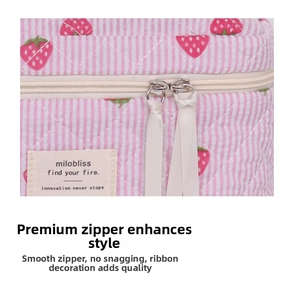 Detail of pink striped quilted bag featuring strawberry prints and dual metal zippers