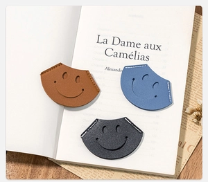 Detailed close-up of colorful PU leather smiley face corner bookmarks on book pages