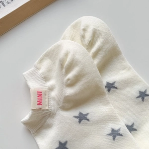 Close-up of white cotton ankle socks with grey star pattern and red MINI tag detail