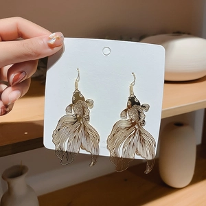 Detailed shot of golden koi fish earrings with intricate hollow-out metal craftsmanship
