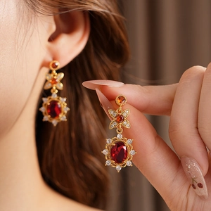 Nahaufnahme von Vintage-Ohrringen mit rotem Zirkon und goldener Fassung im Blumendesign