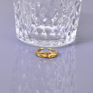 Detail of golden irregular wavy ring placed in front of textured diamond glass