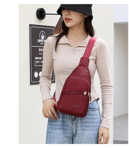 Detail of burgundy oxford fabric chest bag with earphone port and zip compartment