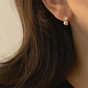 Detail of 925 sterling silver earring with round zircon and hanging white pearl on model