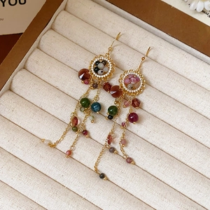 Detailansicht von Vintage Gold-Quastenohrringen mit bunten Perlen auf einer Samtschachtel