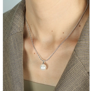 Detailed view of an elegant pearl pendant necklace worn on a silver thin chain