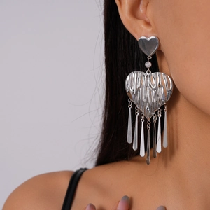 Macro detail of large silver metallic heart fringe earrings with organic lava texture