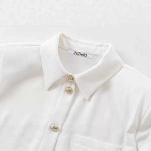 White crepe shirt with structured shoulder pads and embossed gold buttons on the collar