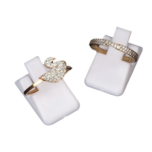 Golden swan and wave ring set with white cubic zirconia on a white display stand