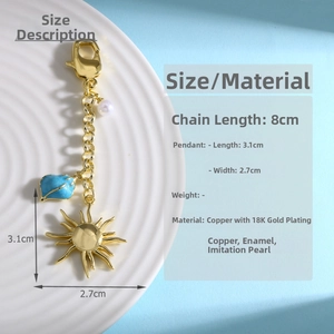 Detail of 18K gold plated sun keychain with blue enamel leaf and pearl on white tray