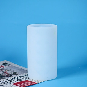 Macro shot of white matte cylindrical silicone mold on a blue background and newspaper