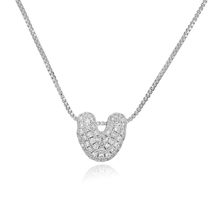 Macro shot of silver U-shaped pendant with cubic zirconia inlay on box chain necklace