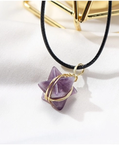 Macro detail of hand-wrapped amethyst Merkaba pendant with gold wire on white silk