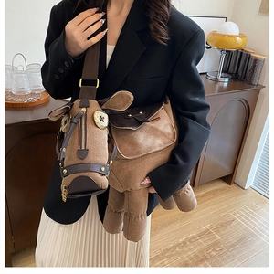Detail of creative horse-shaped brown suede shoulder bag with gold zipper and wide strap