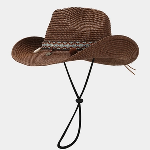 Dettaglio cappello da cowboy in paglia marrone con fascia etnica e nappe decorative