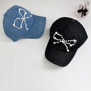 Denim baseball cap featuring a pearl bow design in light blue and black denim washes