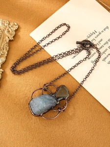 Detail of vintage handmade necklace with raw aquamarine and fluorite in copper setting
