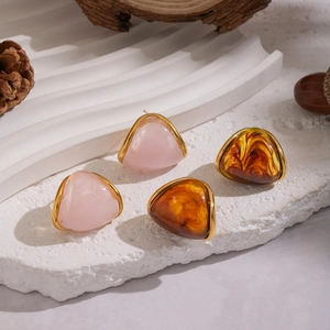 Boucles d'oreilles en résine rose et ambre avec cadre doré sur fond de pierre naturelle