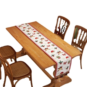Christmas table runner with jacquard snowflake and tassel decorations on wooden table