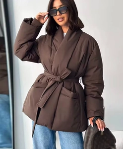 Detail of dark brown oversized belted puffer jacket with lapel and large pockets