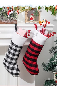 Détail de chaussettes de Noël à carreaux rouges et noirs avec revers blancs près du foyer