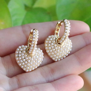 Elegant gold heart hoop earrings with micro-set white pearls shown in a handheld view
