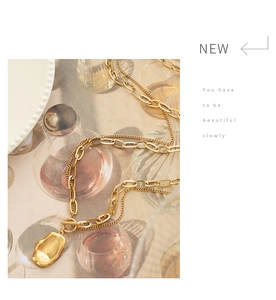 Detail of gold titanium double necklace with OT toggle clasp and irregular pendant on fabric