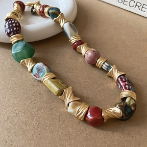 Macro shot of ethnic ceramic flower necklace with colorful beads and gold twisted spacers