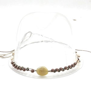 Close-up of bohemian hat band with bronze beads, shells, and a yellow polished stone detail