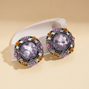 Detail of vintage square purple gem earrings with colored rhinestones on white stone