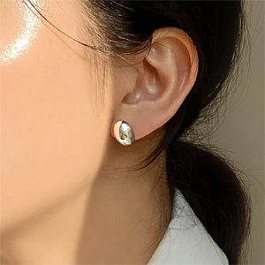 Orecchino a bottone ovale in argento sterling 925 lucido indossato da una modella chic