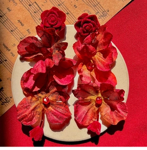 Detailed view of red fabric rose petal earrings with sparkling crystal centers