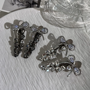 Elegant bow hair clips with crystals in grey and white on a white textured ceramic plate