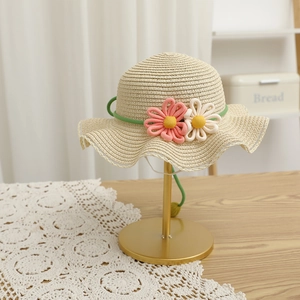 Detail of girls' straw hat featuring handmade crochet flowers and white lace trim edge