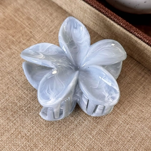 Detail view of the mint blue and white marble textured plumeria flower hair claw clip