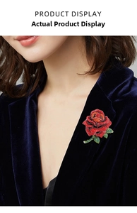 Close-up of a red rhinestone rose brooch pinned on a dark blue velvet blazer lapel