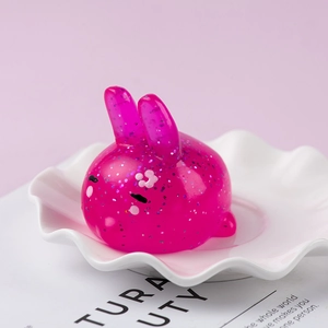 Pink glitter rabbit squishy toy toy on white wave plate for stress relief decor