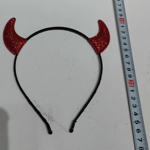 Top-view of Halloween glitter red devil horns headband measured with a ruler for size