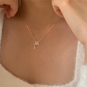 Macro shot of silver sterling crown and bow pendant necklace with teardrop zircon stone