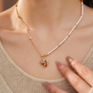 Close-up of 18k gold plated necklace with pearls and zircon heart pendant on model