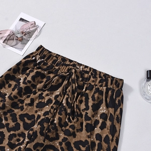 Dettaglio dei pantaloni leopardati con coulisse elastica in vita su sfondo materico