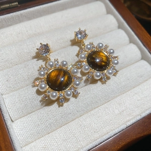 Close-up of vintage tiger eye stud earrings with pearls and zircon in a jewelry box