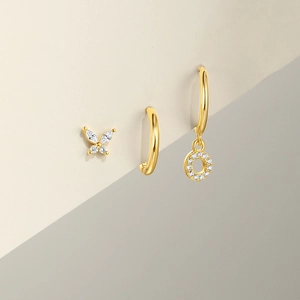 Detailed set of silver bow stud, golden hoop, and sparkling cubic zirconia drop earrings