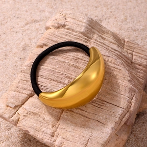 Minimalist golden crescent moon hair cuff with black elastic band on natural stone