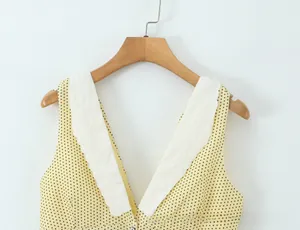 Detail of yellow polka dot V-neck top with white lace embroidery on neckline