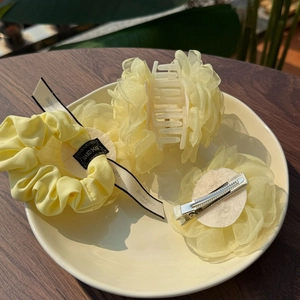 Detail of yellow organza flower hair clips and scrunchie set on a decorative plate
