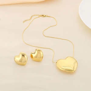 Ensemble collier et boucles d'oreilles cœur doré sur tissu beige doux