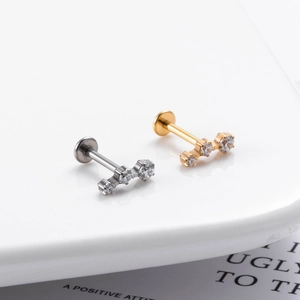 Macro shot of silver and gold G23 titanium push-pin studs with three-stone zircon accents
